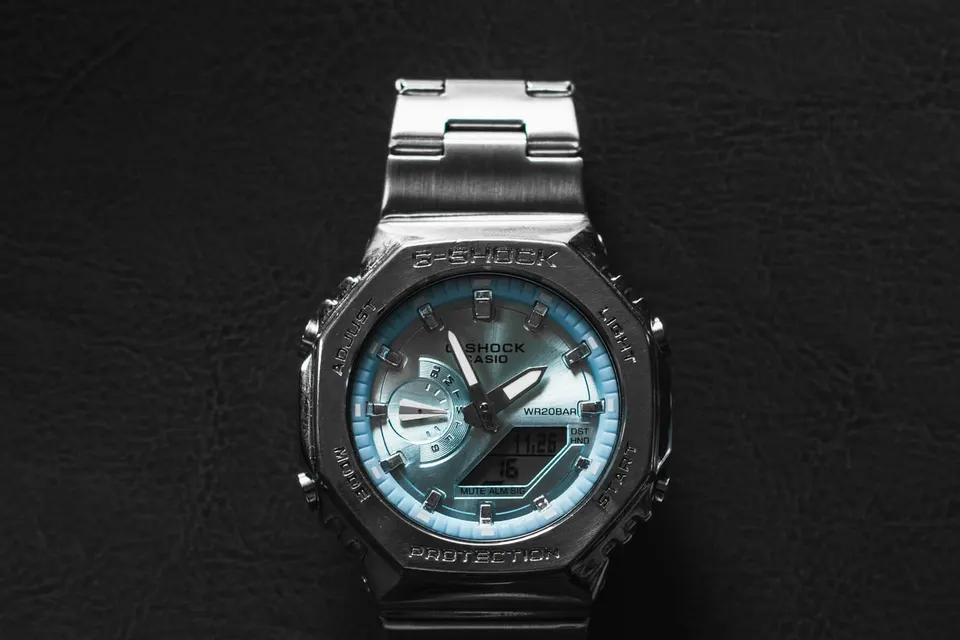 Vollmetall-G-Shock mit eisblauem Zifferblatt von oben auf dunklem Leder, achteckige Lünette mit G-SHOCK-Gravur, Edelstahlband