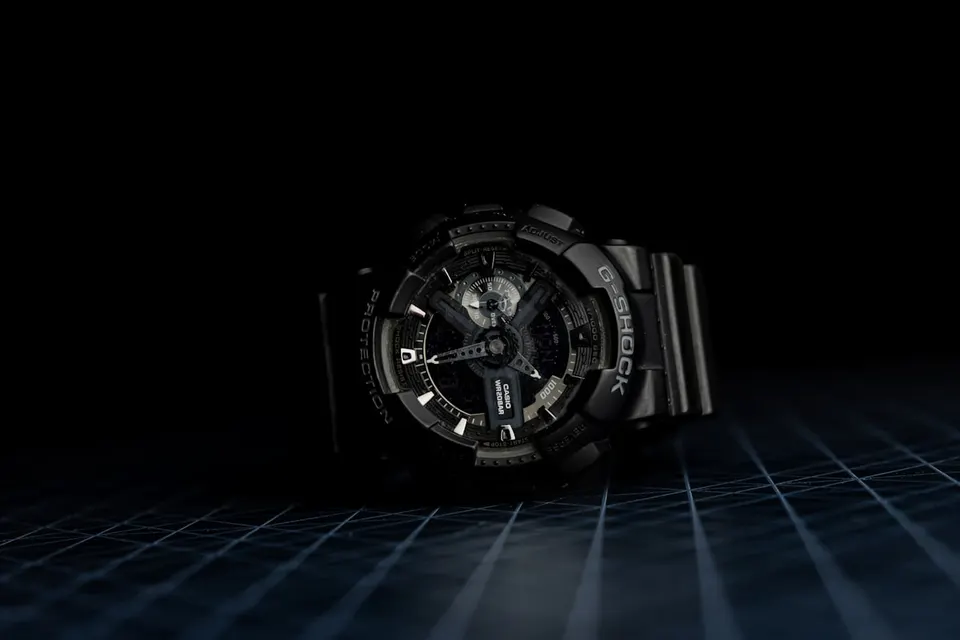 Schwarze Casio G-Shock aus Resin, liegend im Dunkeln aufgenommen, der umlaufende Schutzrand überragt Glas und Bedienknöpfe