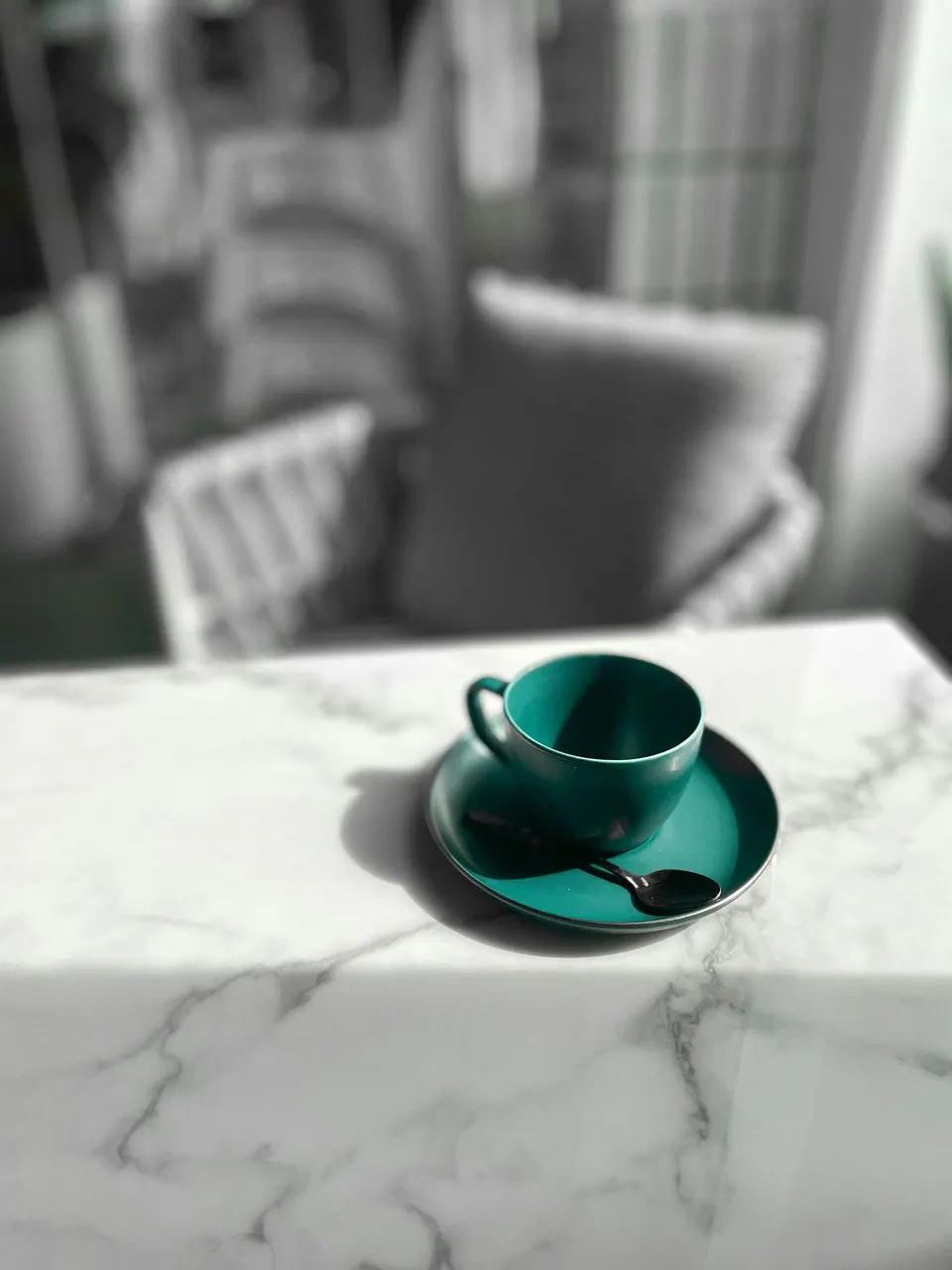 Grüne Tasse mit Untertasse auf einem Marmortisch mit grauer Äderung