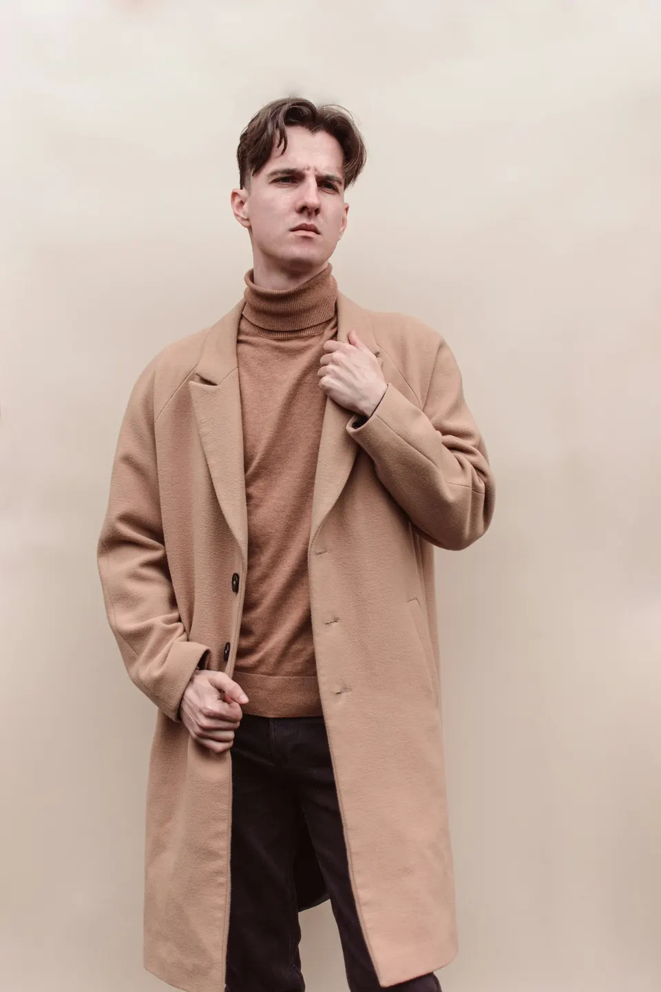 Mann in camelfarbenem Rollkragenpullover unter einem Mantel im selben Ton