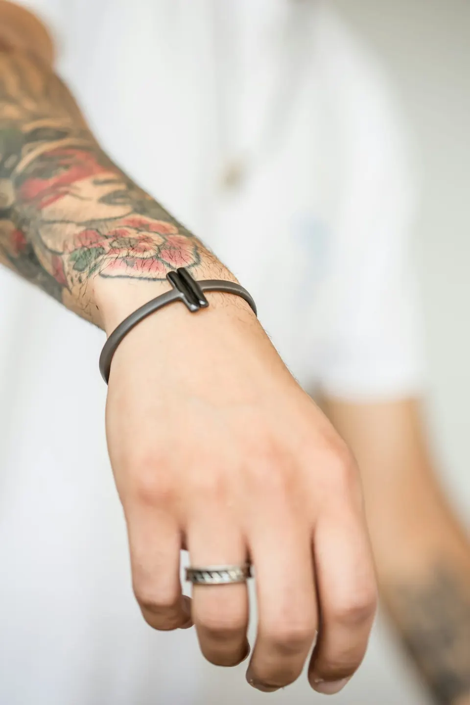 Nahaufnahme eines Männerhandgelenks mit mattschwarzem Armband und silbernem Ring