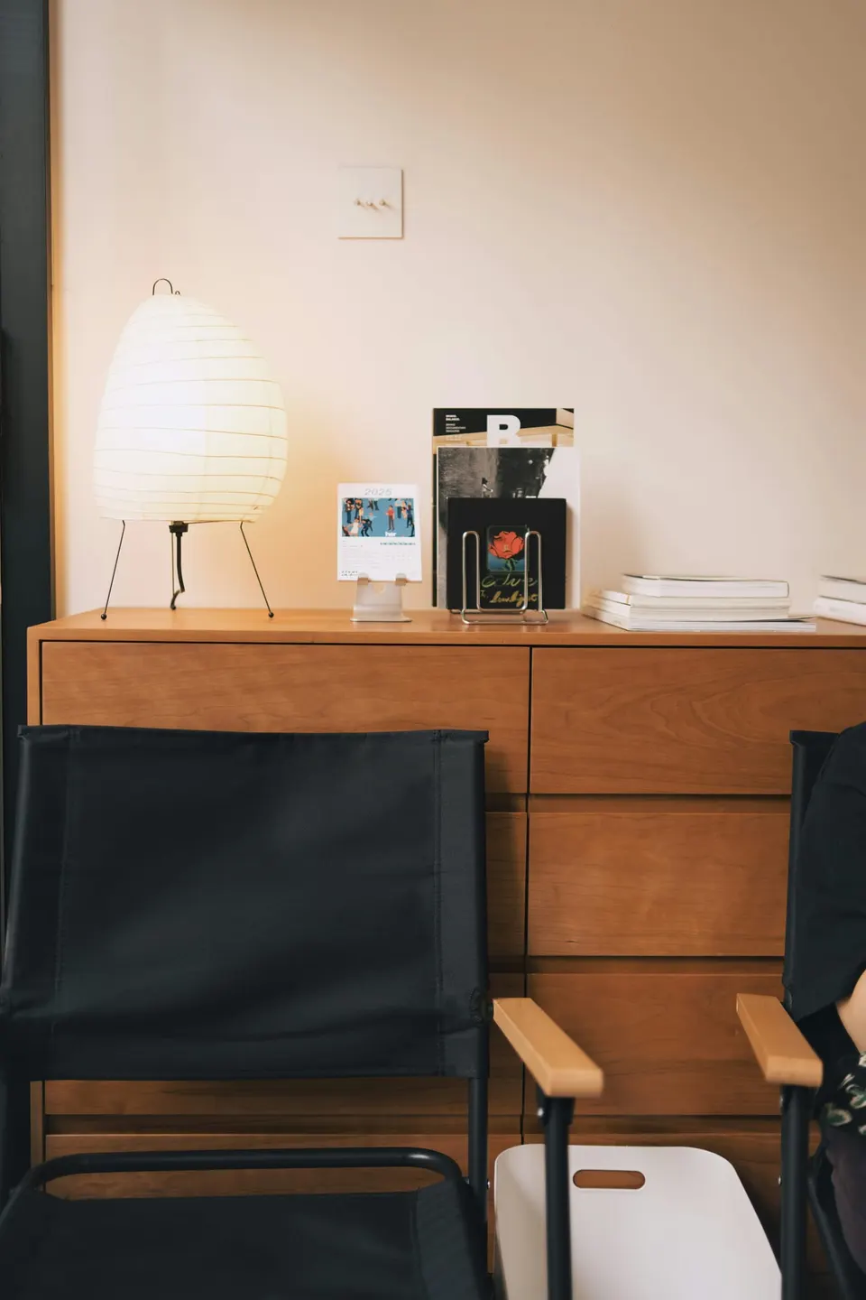 Tropfenförmige Papierleuchte auf einer Holzkommode in einem ruhigen, warm beleuchteten Zimmer