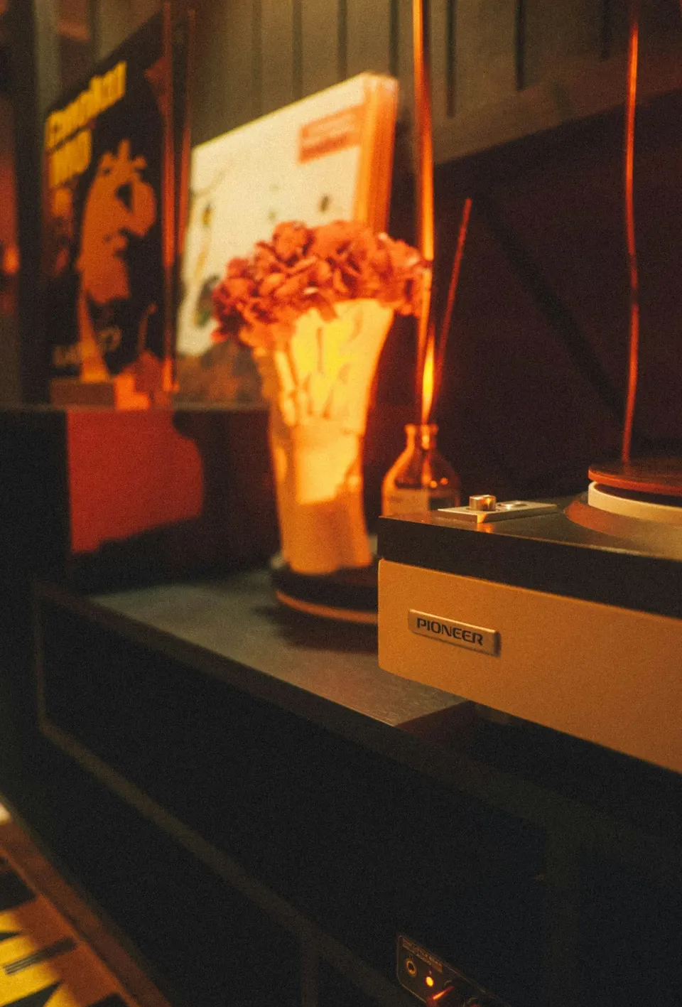 Vintage-Plattenspieler auf einer Kommode mit roten Blumen und Schallplatten daneben