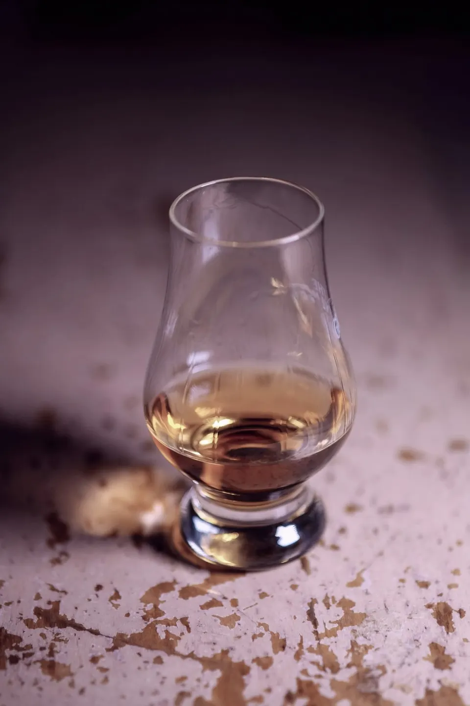 Whiskyglas mit bernsteinfarbenem Inhalt im warmen Abendlicht