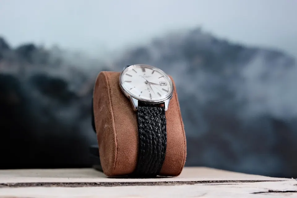 Vintage-Automatikuhr mit strukturiertem Lederband, geschlossen um ein Wildleder-Uhrenkissen