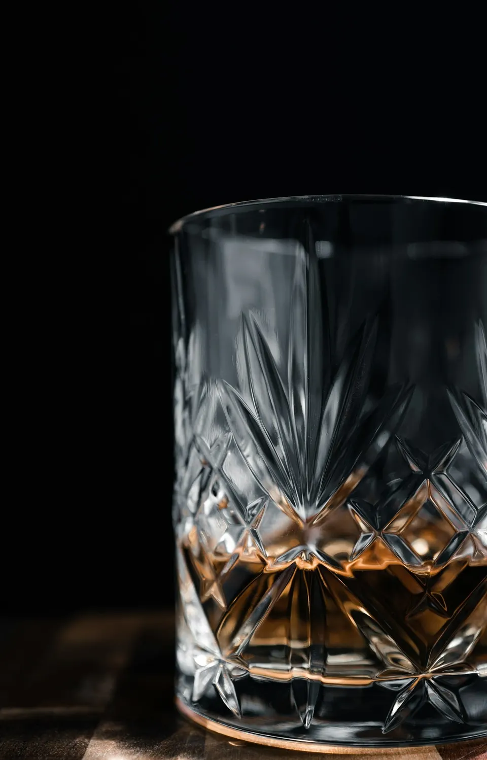 Whiskyglas mit Schliff auf einem Holztisch in warmem Abendlicht